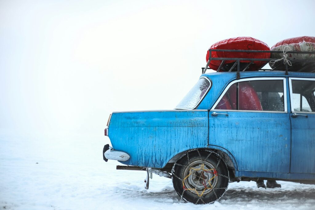 blue sedan with chain on tire parking on snowfield at daytime